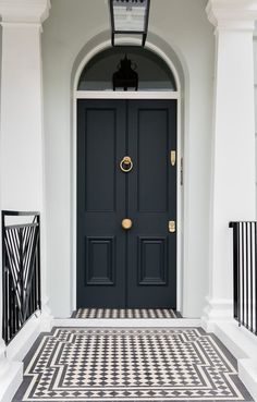 a black and white checkered tile floor in front of a blue door with gold handles