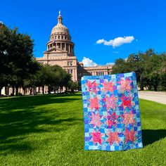 a quilt is on the grass in front of a large building with a domed dome