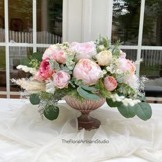 a vase filled with pink and white flowers sitting on top of a table next to a window