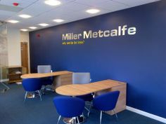 an office with blue chairs and a sign on the wall that says miller macaffe