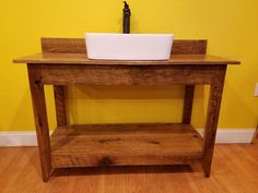 a bathroom sink sitting on top of a wooden table next to a yellow wall and wood floor