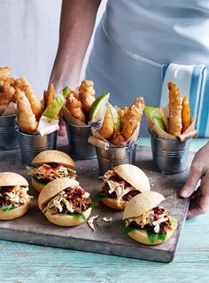 a tray filled with chicken sliders and fries on top of a wooden table next to a cup of dipping sauce