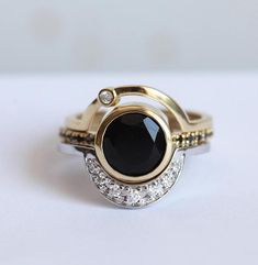 two gold rings with black and white stones on them, one has a diamond set in the middle