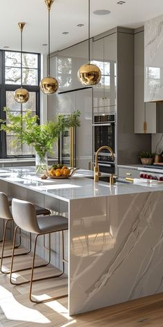 a large kitchen with marble counter tops and gold pendant lights hanging from the ceiling over the island