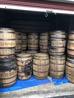 several wooden barrels stacked on top of each other in front of a garage door with blue tarp