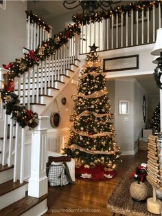 a decorated christmas tree in the middle of a living room with stairs and banisters