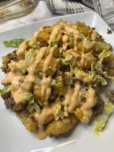 a white plate topped with meat covered in gravy and lettuce leaves