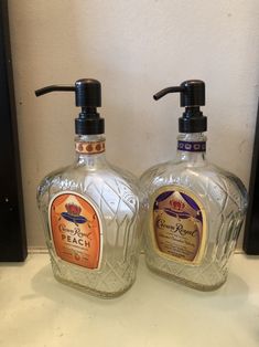 two glass bottles with soap dispensers on top of a white countertop