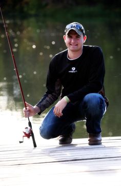 a man kneeling down while holding a fishing pole