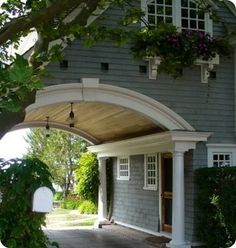 a gray house with white trim and flowers in the window boxes on the front porch