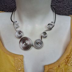 Sharm Open Metal Choker. Silver Necklace. Modern Style. Spiral Aluminum Silver Necklace. Statement Necklace.Bridal Jewelry. Bold Designe. Handmade. This spiral shape necklace is a statement piece, the perfect accessory to complete a stunning outfit look. Ideal for a casual fashion style. Materials:  - Aluminum wire (3 mm). The material I use to wrap aluminum wire, that means, is not heavy at all. Aluminum is lightweight and will never tarnish. I give it a slightly hammered texture and wrap the glass stone with it. SIZE: The necklace is 54 cm/ 21 inches in circumference  COLOR:  Silver, aluminum  wire Try to keep it away from water. Shipping time: This item is finished product and it will be sent immediately. Shipping time is 1 to 4 weeks (depends of your Custom office and Post office).  Th Glass Spiral Necklace, Silver Spiral Jewelry For Weddings, Silver Spiral-shaped Wedding Jewelry, Spiral Silver Wedding Jewelry, Silver Spiral Wedding Jewelry, Choker Silver, Wire Jewellery, Metal Choker, Aluminum Jewelry