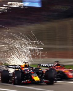 a red and yellow race car driving down a track with fireworks in the air behind it