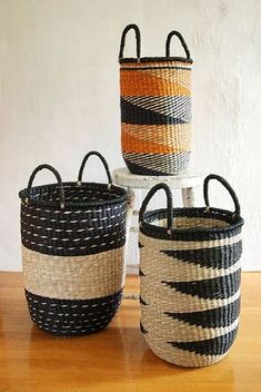 three baskets sitting on top of a wooden table next to each other, one with an orange and black stripe