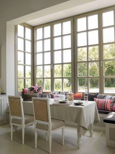 a dining room with large windows and white furniture