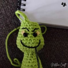 a crocheted green creature with black eyes