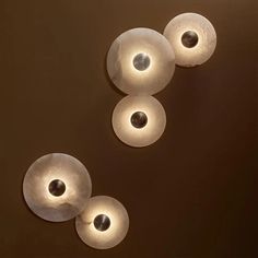 three circular lights hanging from the ceiling in front of a brown wall with circles on it