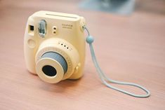 a yellow camera sitting on top of a wooden table next to a blue corded phone