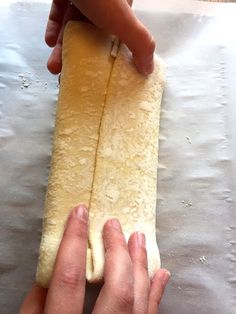 two hands are holding a long piece of bread