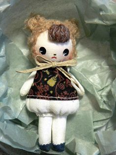 a small doll is sitting on some paper