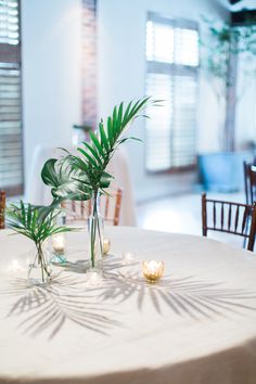 the table is set with candles and palm leaves