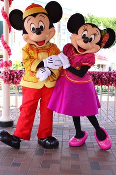 two mickey and minnie mouse characters standing next to each other