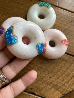 three donuts with sprinkles on them are being held by a person's hand