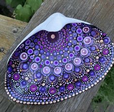 a purple and white plate sitting on top of a wooden table next to a fence