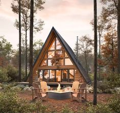 a - frame cabin in the woods with two chairs and a fire pit on the ground