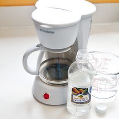 a white coffee maker sitting on top of a counter next to a bottle of water