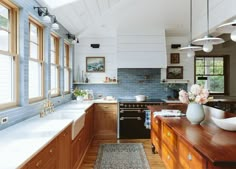 a kitchen with blue tiles and wooden cabinets, white counter tops and wood flooring