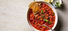 a white bowl filled with chili and tortilla chips on top of a table