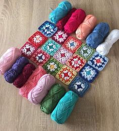 several balls of yarn are laid out on the floor next to crochet squares