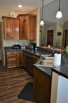 a kitchen with wooden cabinets and black counter tops in the middle of an open floor plan