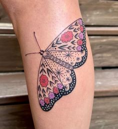 a butterfly tattoo on the leg with flowers and leaves around it's wings is shown