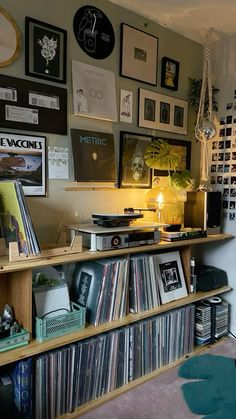 a room filled with lots of records and pictures on the wall next to a lamp