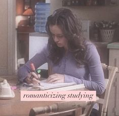 a woman sitting at a kitchen table writing on a notebook with the caption romanticizing studying