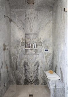 a bathroom with marbled walls and flooring, including a white bench in the middle