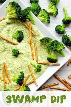 broccoli and carrot sticks on a white plate with green dip in the middle