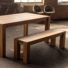 a wooden table with two benches in front of it on a brick floored room