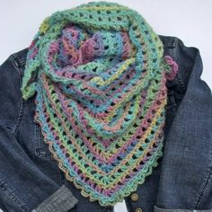 a multicolored crocheted scarf hanging from a denim jacket