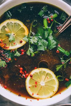 a bowl full of soup with lemons and garnishes on the side