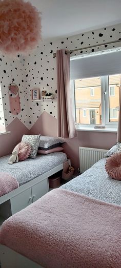 two beds in a room with polka dot wallpaper on the walls and pink bedding