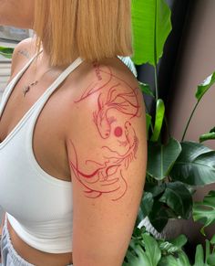 a woman with a dragon tattoo on her arm and shoulder, next to a potted plant