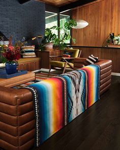 a living room filled with furniture and lots of plants on top of wooden flooring