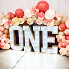 a one sign surrounded by balloons and streamers with the word'one'spelled out