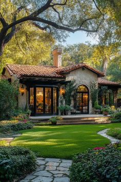 a house with lots of plants and trees in the front yard, surrounded by lush green grass