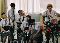 a group of young people sitting next to each other in front of a bike with wheels