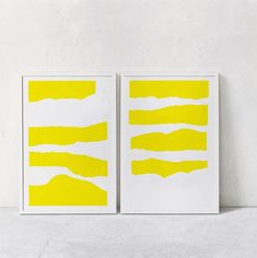 two yellow and white paintings sitting on top of a table