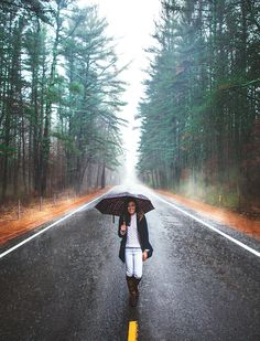 a woman walking down the road with an umbrella