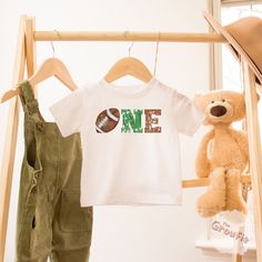 Celebrate your little one's 1st birthday with this 1st year down shirt. And dress up the whole family with these matching football birthday outfits! SHIRT DETAILS * Bella+Canvas - Adult, Youth, and Toddler shirts * Rabbit Skins - Baby shirts and bodysuits * Next Level - Women's tank tops * Gildan - alternative option if the primary brand is out of stock * 100% soft cotton SIZING * Our shirts are unisex - Run true to size and have a relaxed fit. Order one size smaller for a further slim fit. * If you are unsure about what size to order, please refer to the size chart in the photos or reach out to us. * To measure, lay your favorite shirt flat. Measure armpit to armpit and the length, then compare to the size chart in the photos. * Incorrect size can not be refunded or exchanged. DIRECT TO G Football First Birthday Outfit, Number Print Short Sleeve Top For First Birthday, 1st Down Football Birthday Party, 1 Birthday Boy Themes, Photo Collage Ideas, 1st Birthday Boy Themes